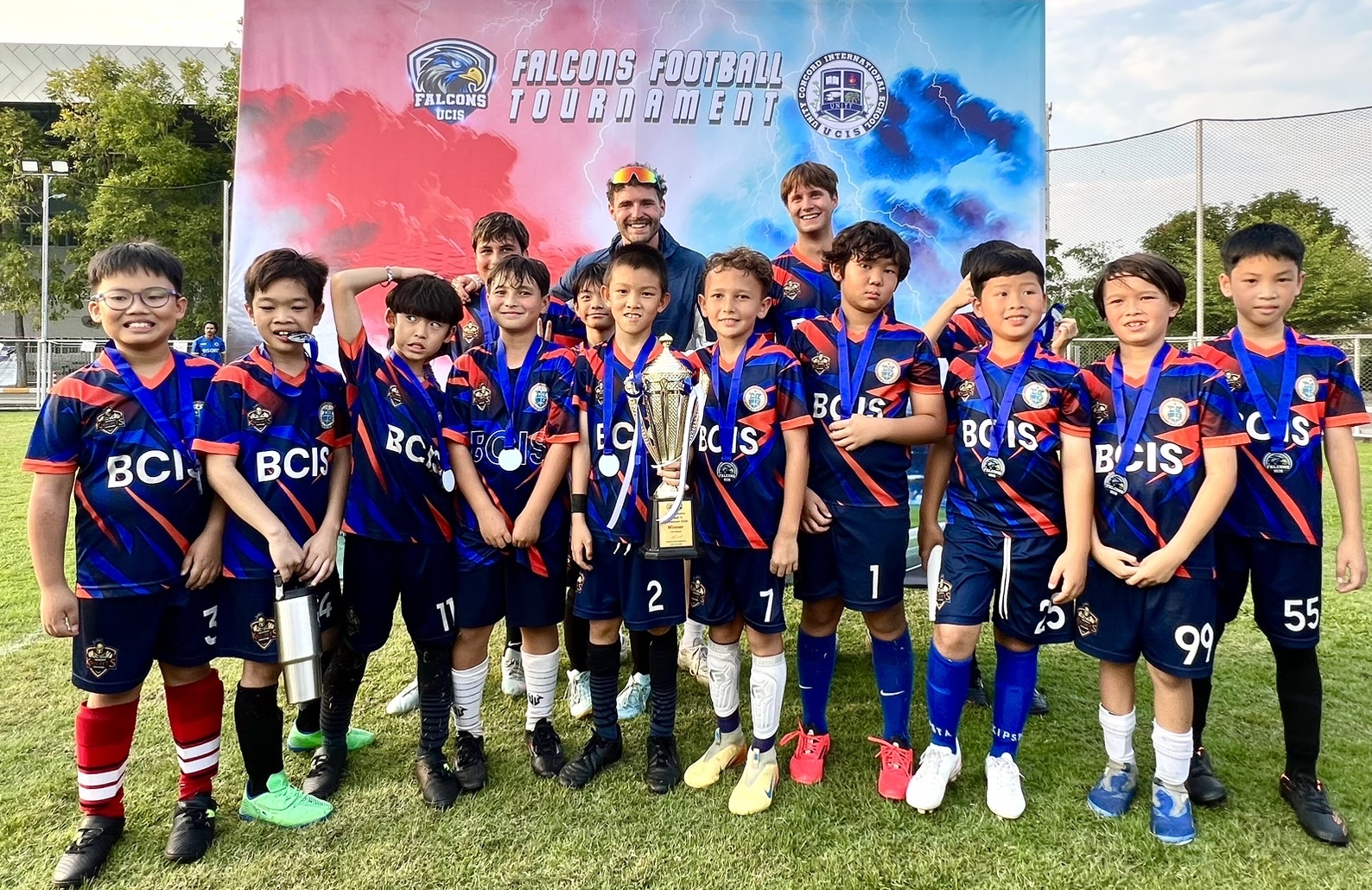 U10 BCIS Knights football team celebrating with the Falcons Football Tournament trophy