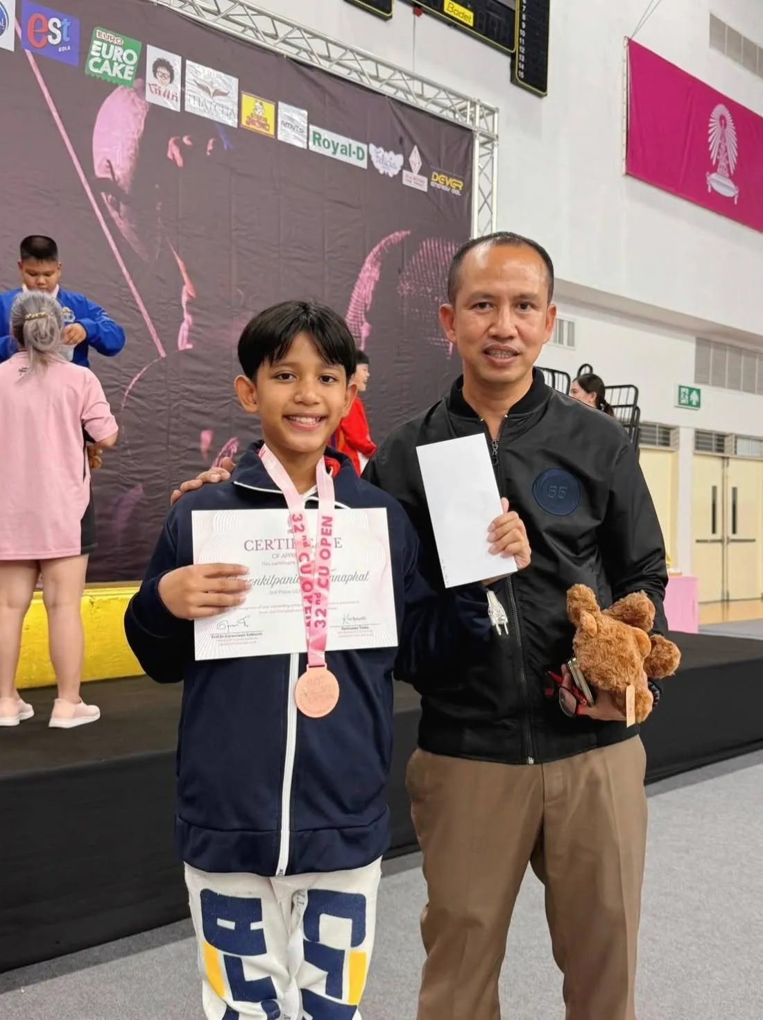 Pluem with his medal and certificate and his coach at the competition