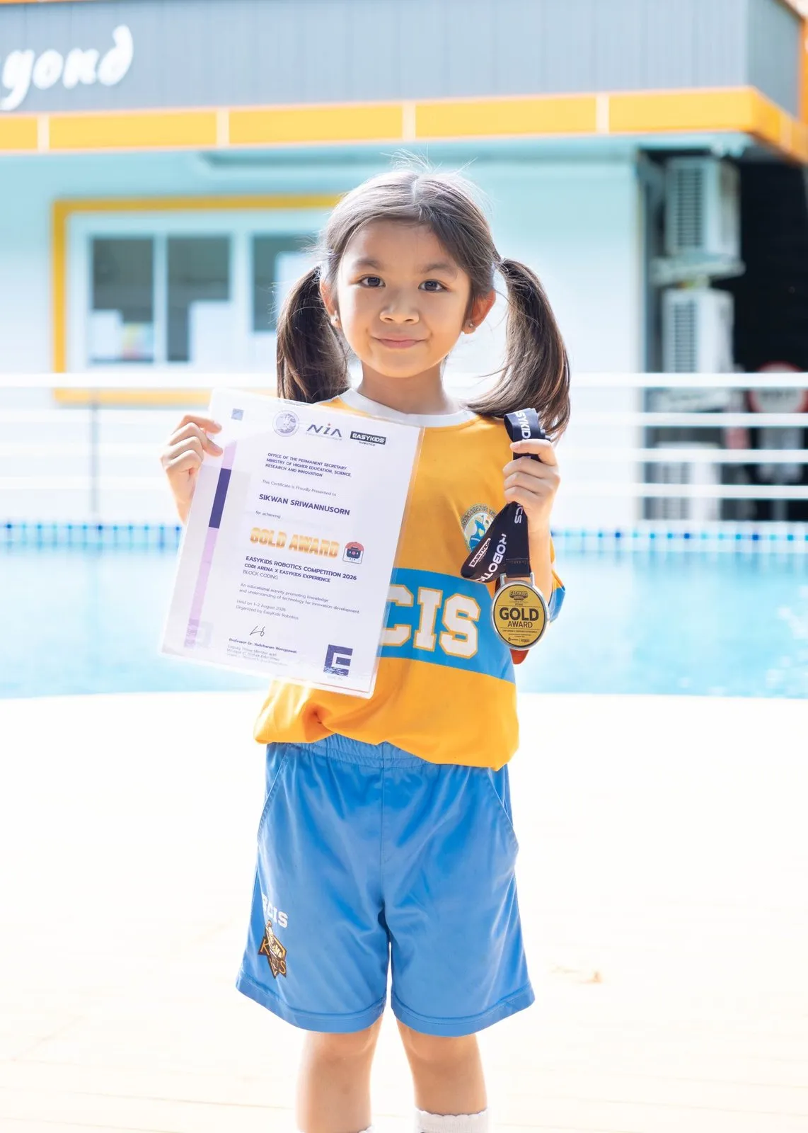 Tubtim holding her certificate and gold medal at school