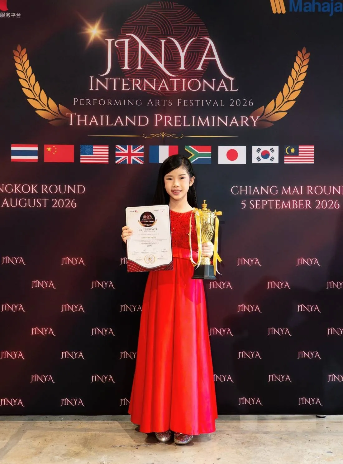 Patricia in a red dress with her violin, trophy and certificate