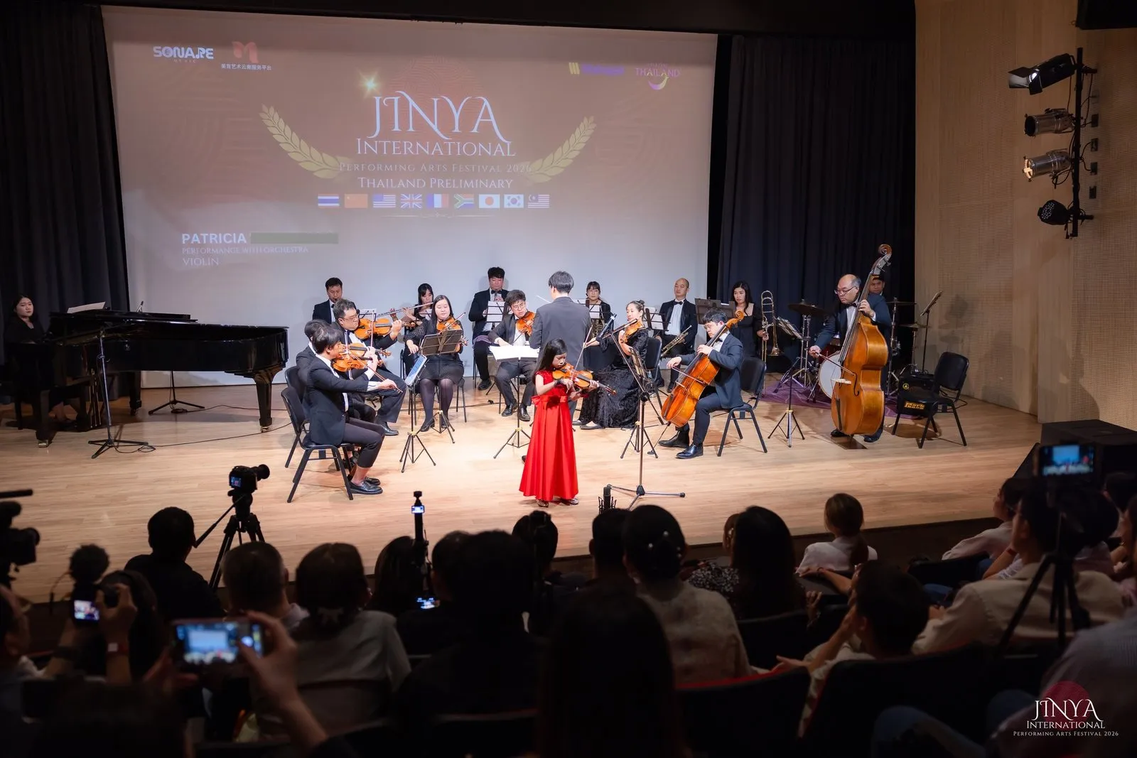 Patricia performing violin with the orchestra on stage