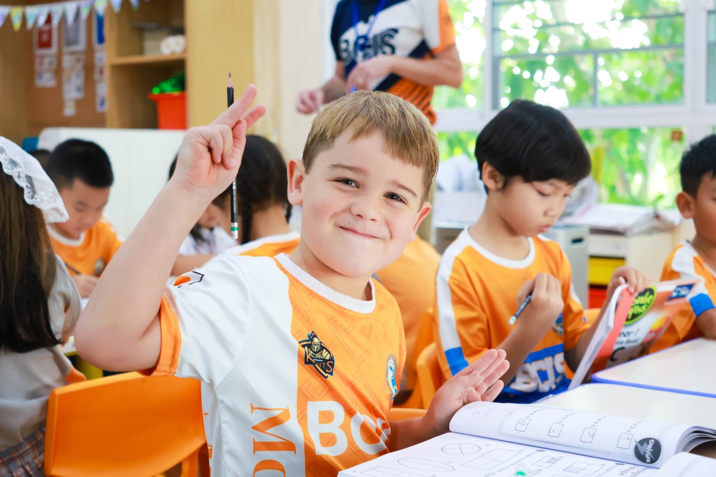 Primary student eagerly raising hand in a BCIS classroom