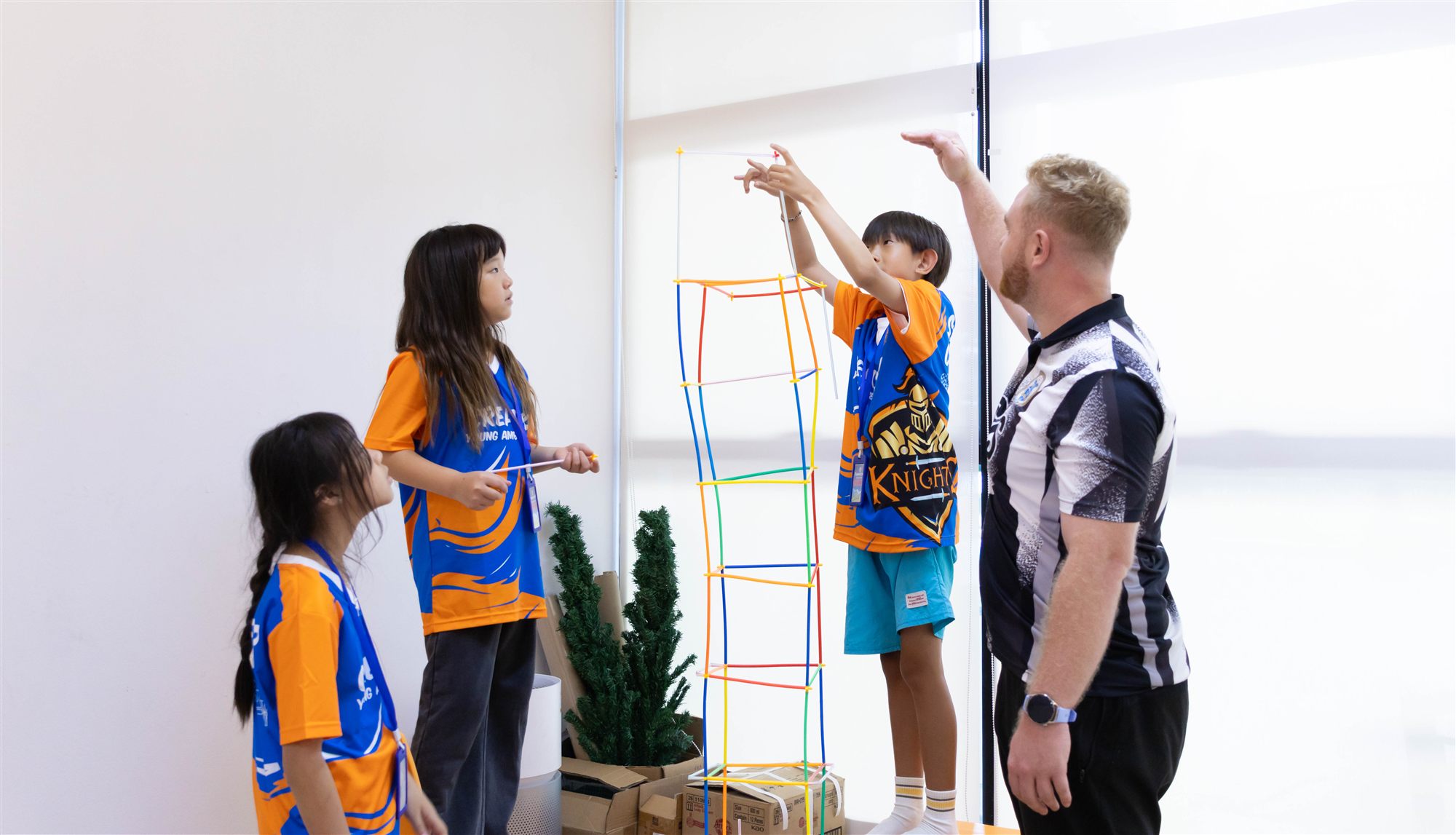 Campers building a straw tower together as a team challenge